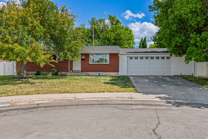 Ranch-style residence featuring a brick facade and a multi-car garage with white panel doors