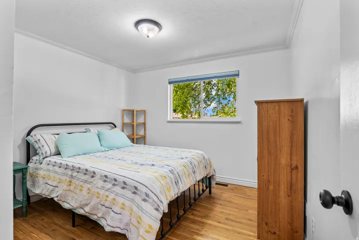 Room featuring wood-finish flooring, a white window frame, and crown molding