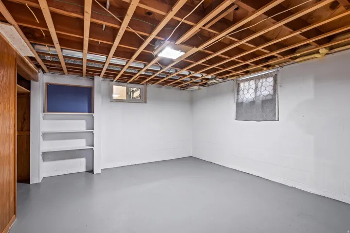 Unfinished lower level featuring exposed ceiling joists, painted concrete walls, and a painted concrete floor