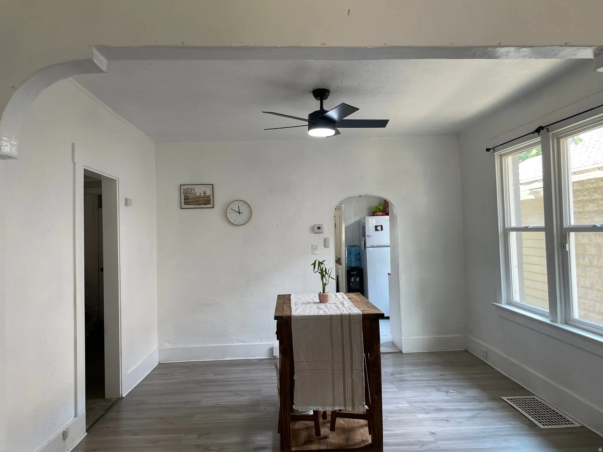 Spacious interior room featuring light-toned wood-finish flooring, white walls, and a modern ceiling fan with integrated lighting