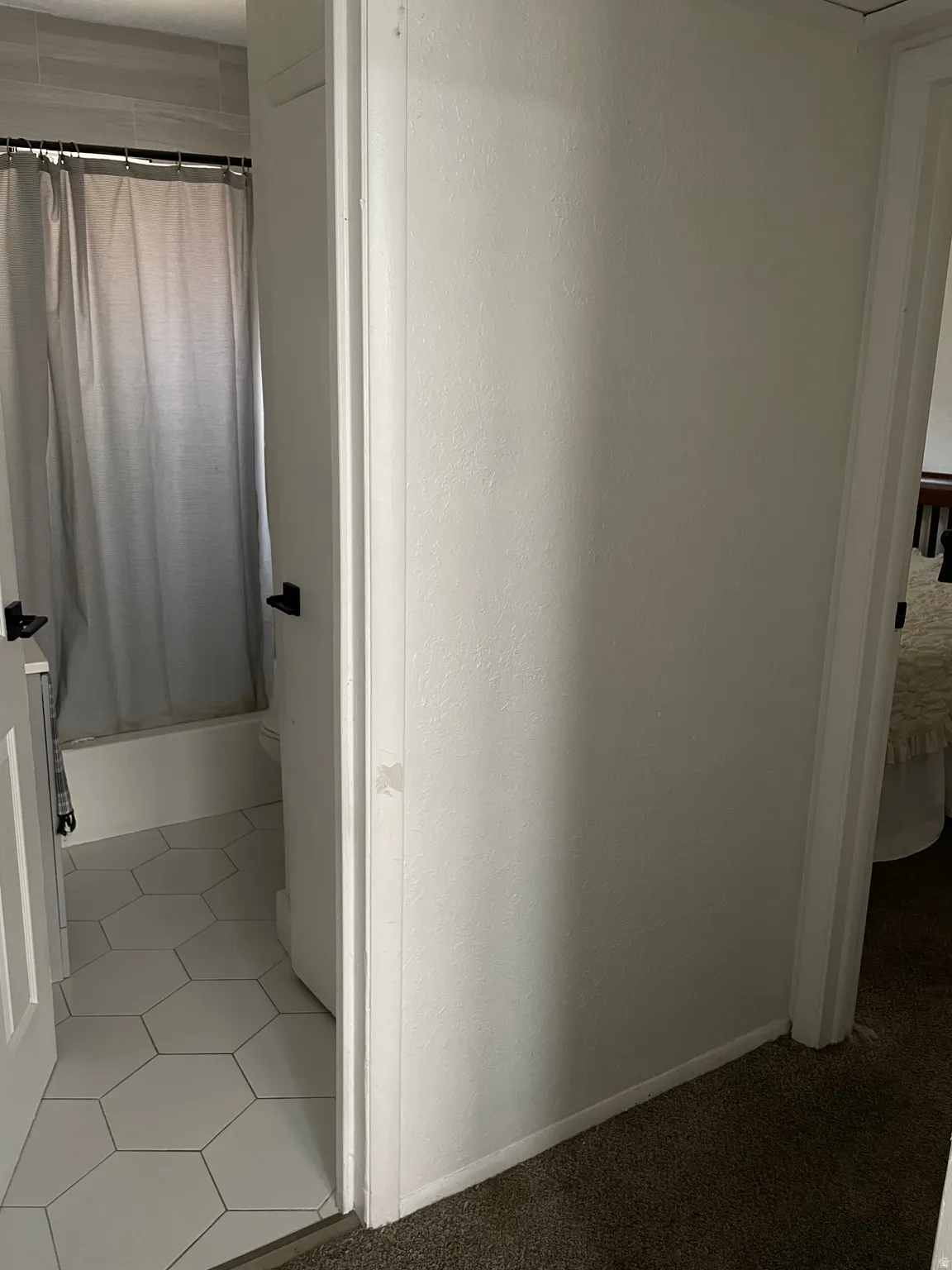 Bathroom featuring white hexagonal floor tiles, a white bathtub, and light grey wall tiles