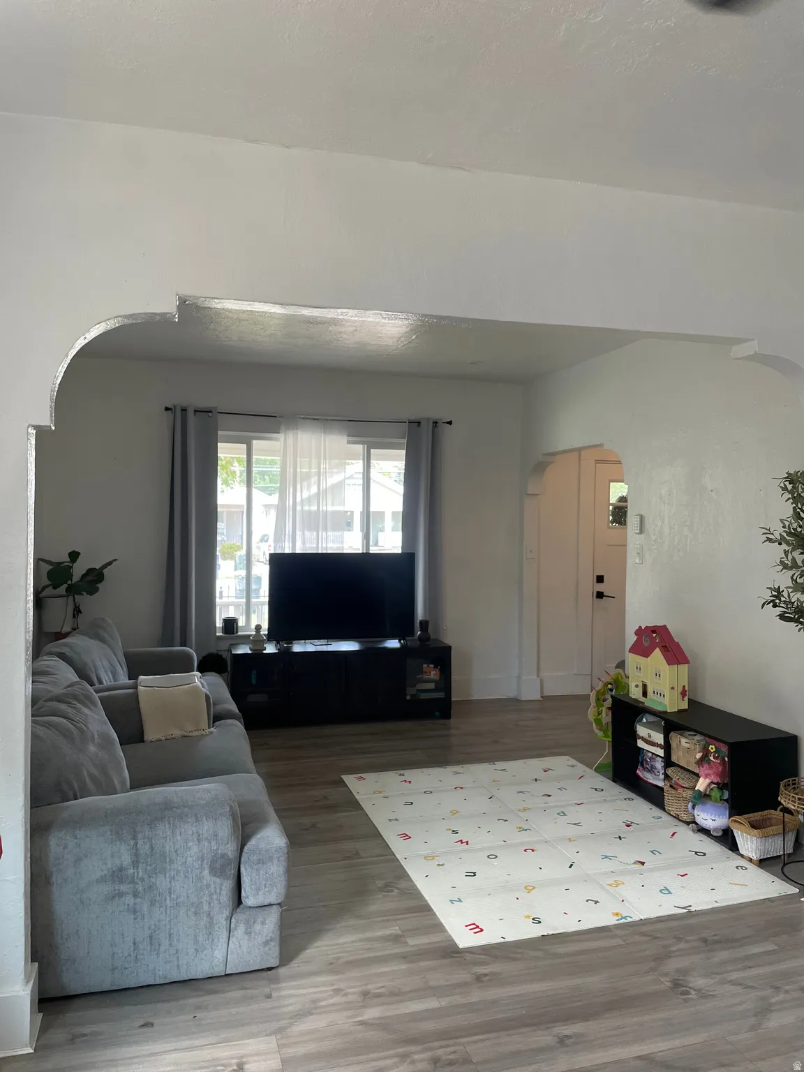 Expansive living area featuring arched doorways, wood-finish flooring, and white baseboards