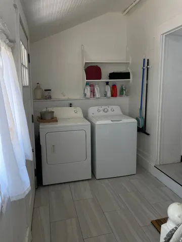 Dedicated laundry area featuring a washer and dryer, tile flooring, white walls, and built-in shelving