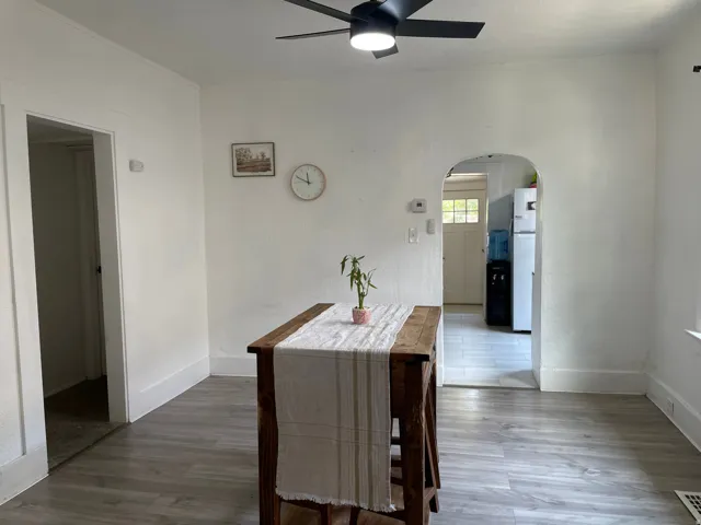 Interior space with wood-finish flooring and a contemporary black ceiling fan with integrated lighting