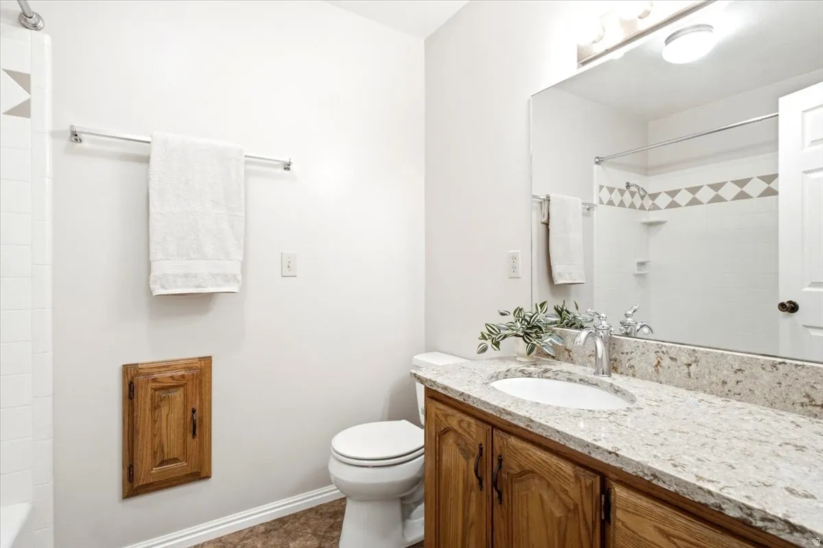 Main bathroom with updated quartz countertop, tile surround and cast iron tub