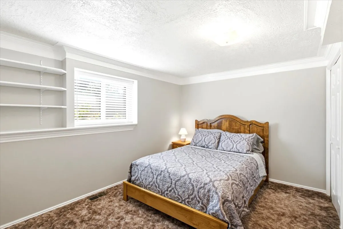 Large bedroom with built in shelving, crown molding and desk area ( not pictured). Daylight window