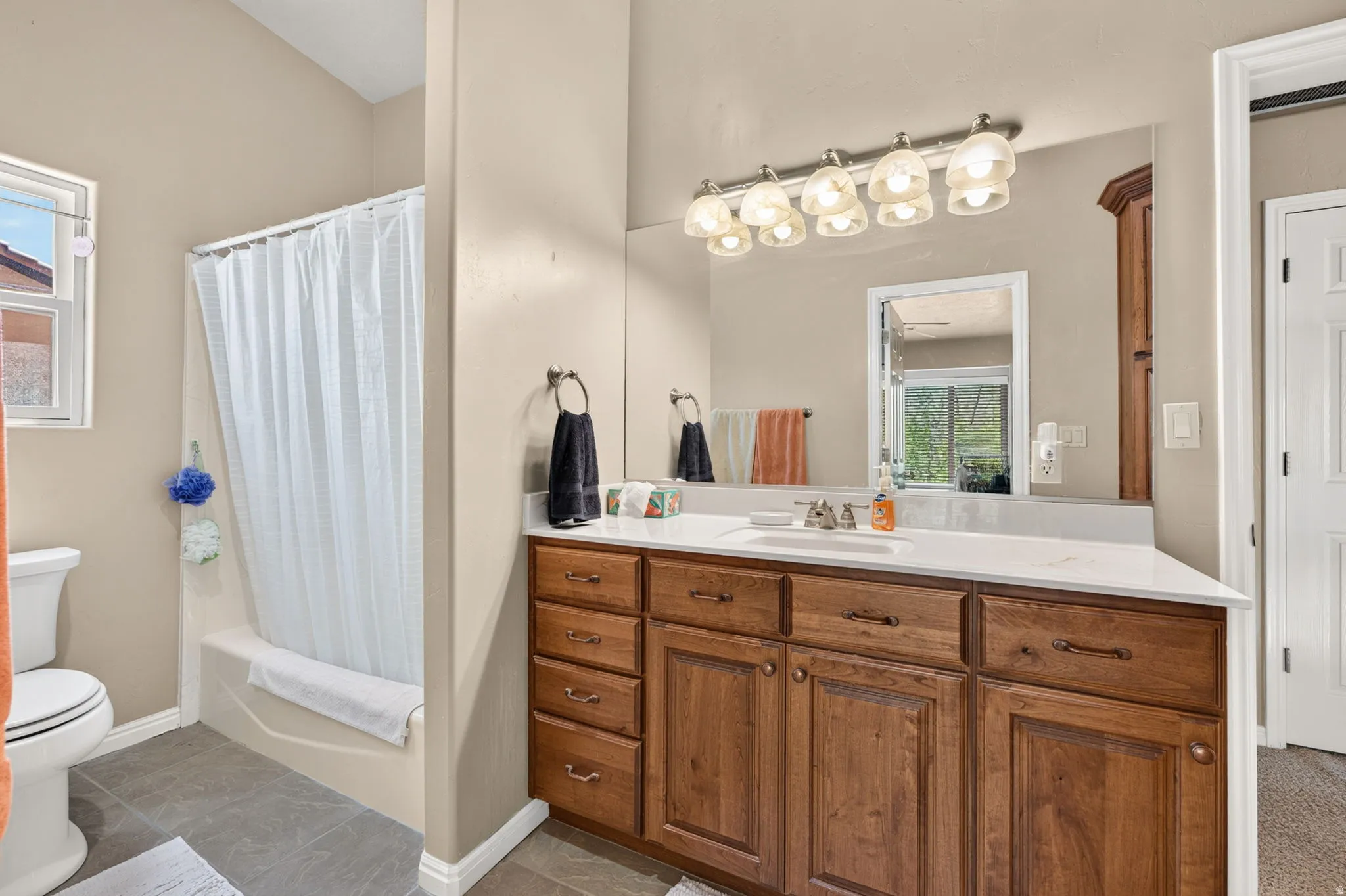 Bathroom featuring a wood-finish vanity with ample storage, a white countertop, and an integrated sink