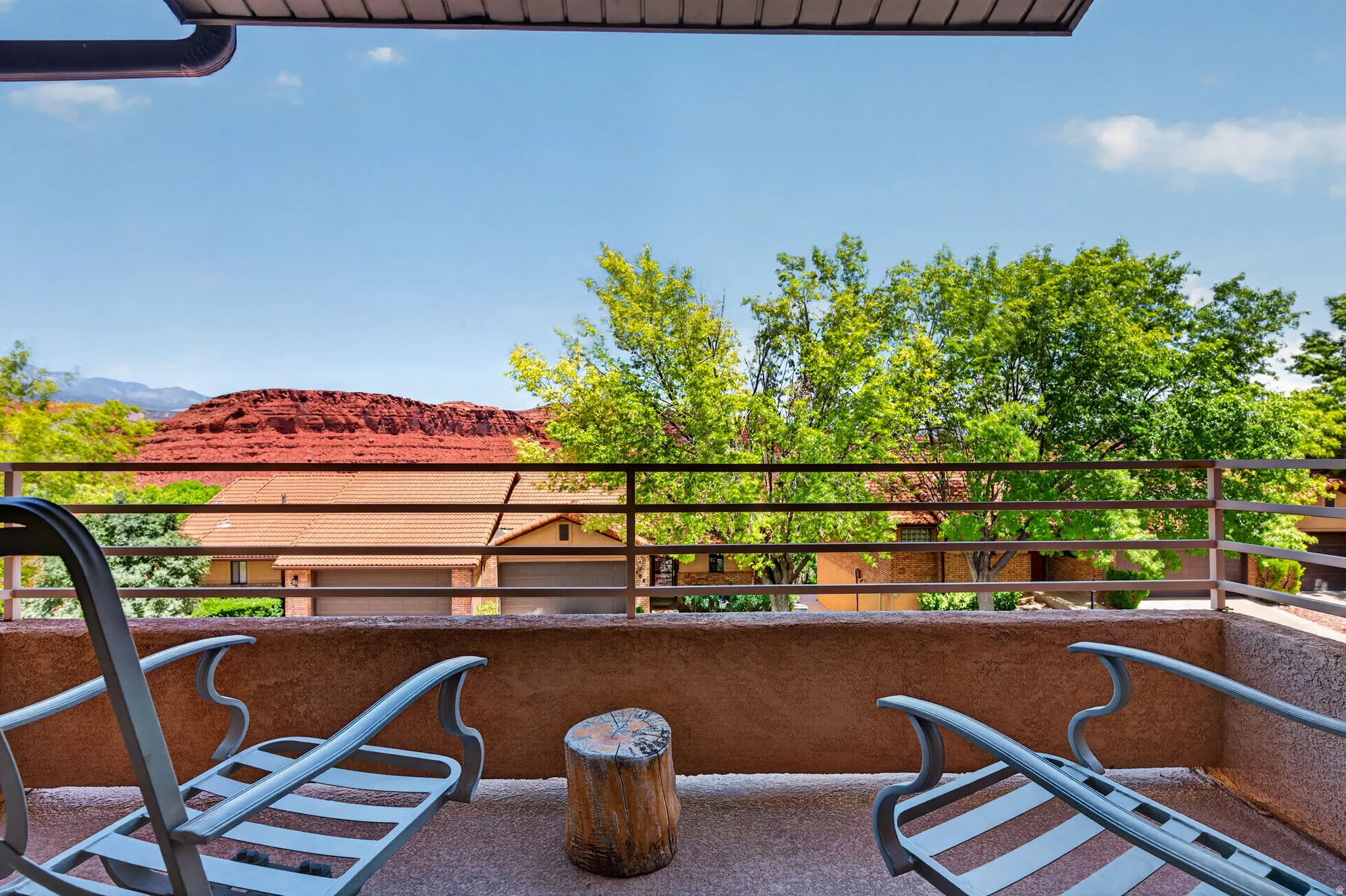 Private balcony with textured flooring, a metal railing, and an overhead soffit