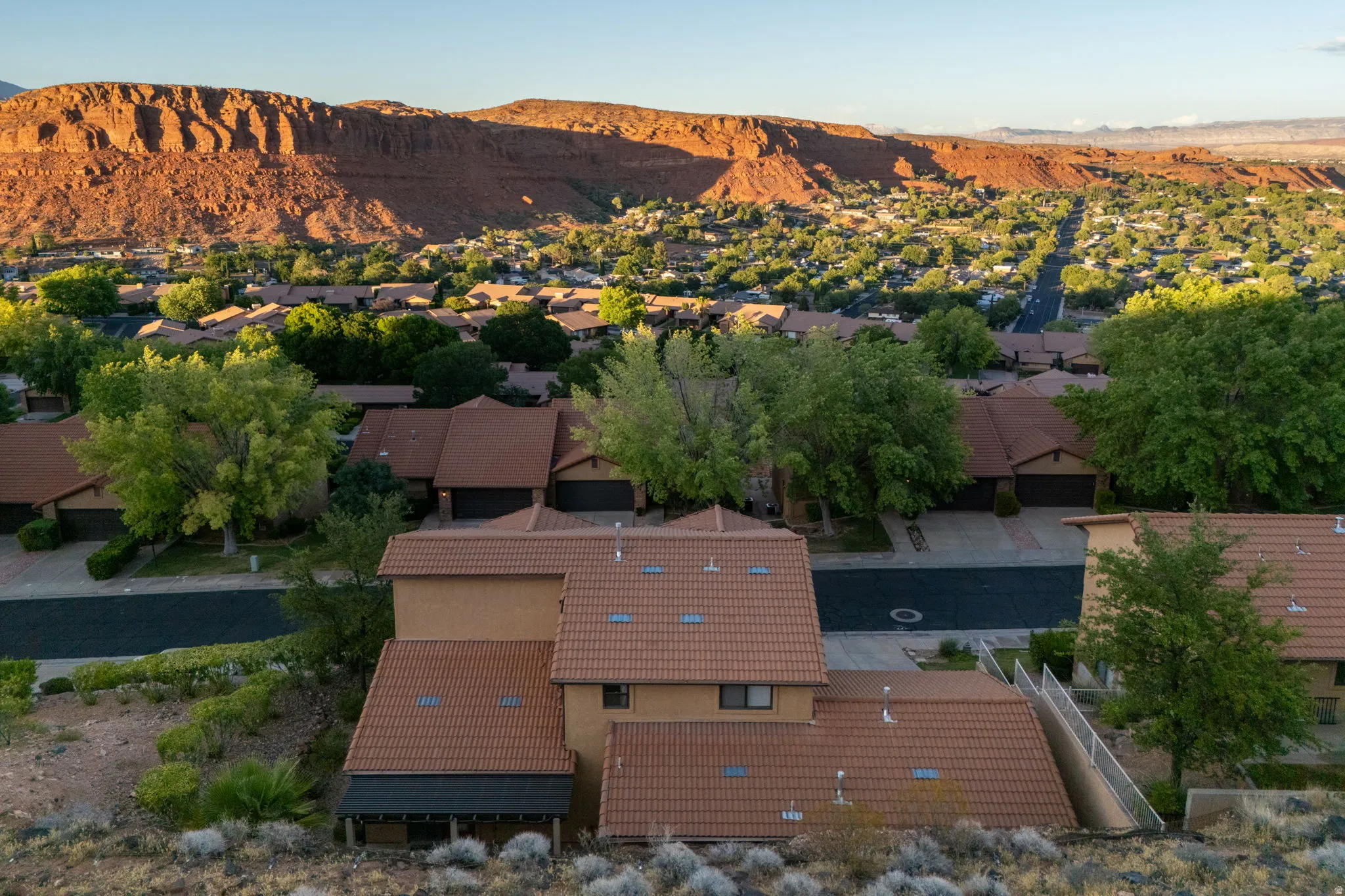 Terracotta tile roofs define this property, situated among a neighborhood of similar homes with mature trees