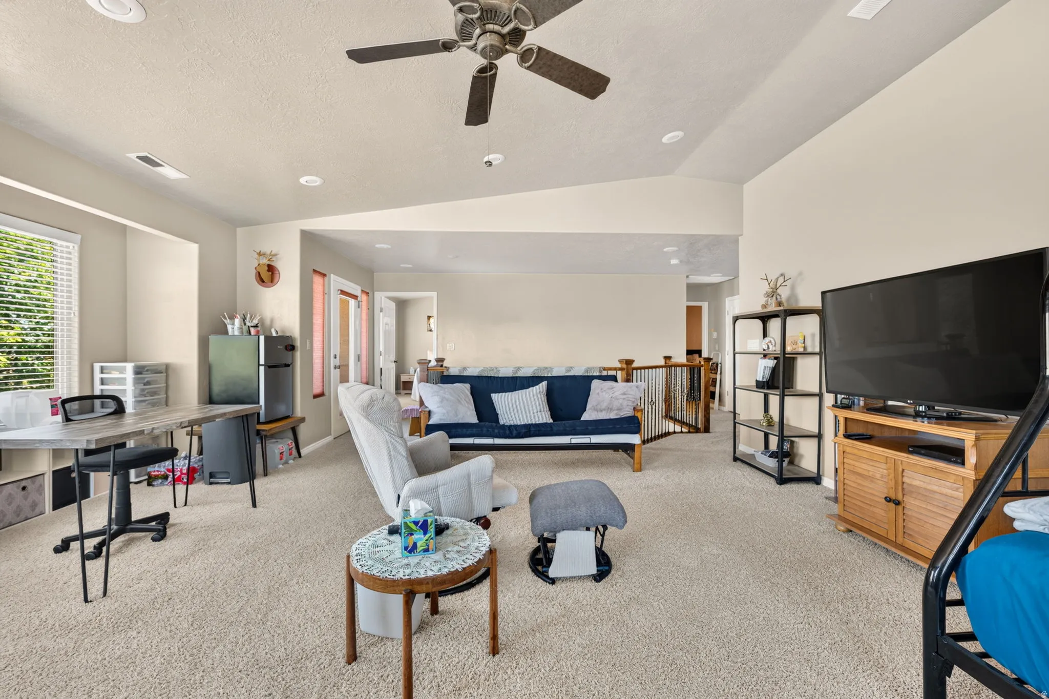 Spacious carpeted room featuring vaulted ceilings, recessed lighting, and a ceiling fan