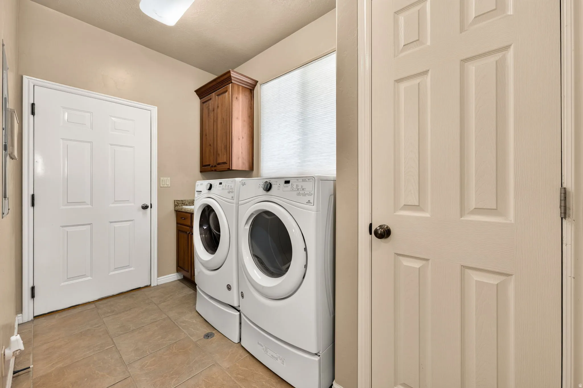 Laundry room featuring tile flooring, built-in cabinetry, and a window for natural light