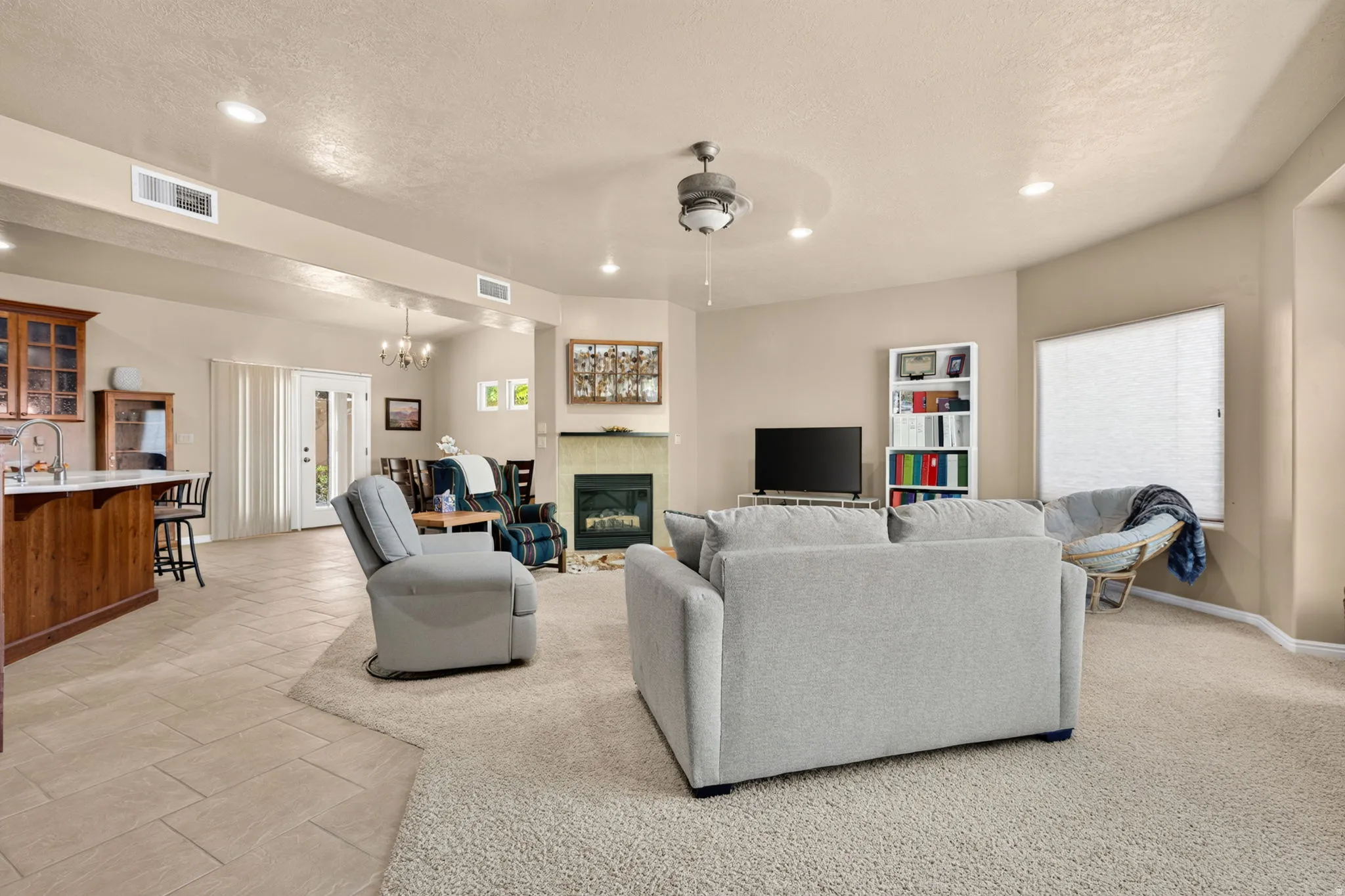 Open-concept living space featuring a fireplace with a light-colored mantel, recessed lighting, and a ceiling fan