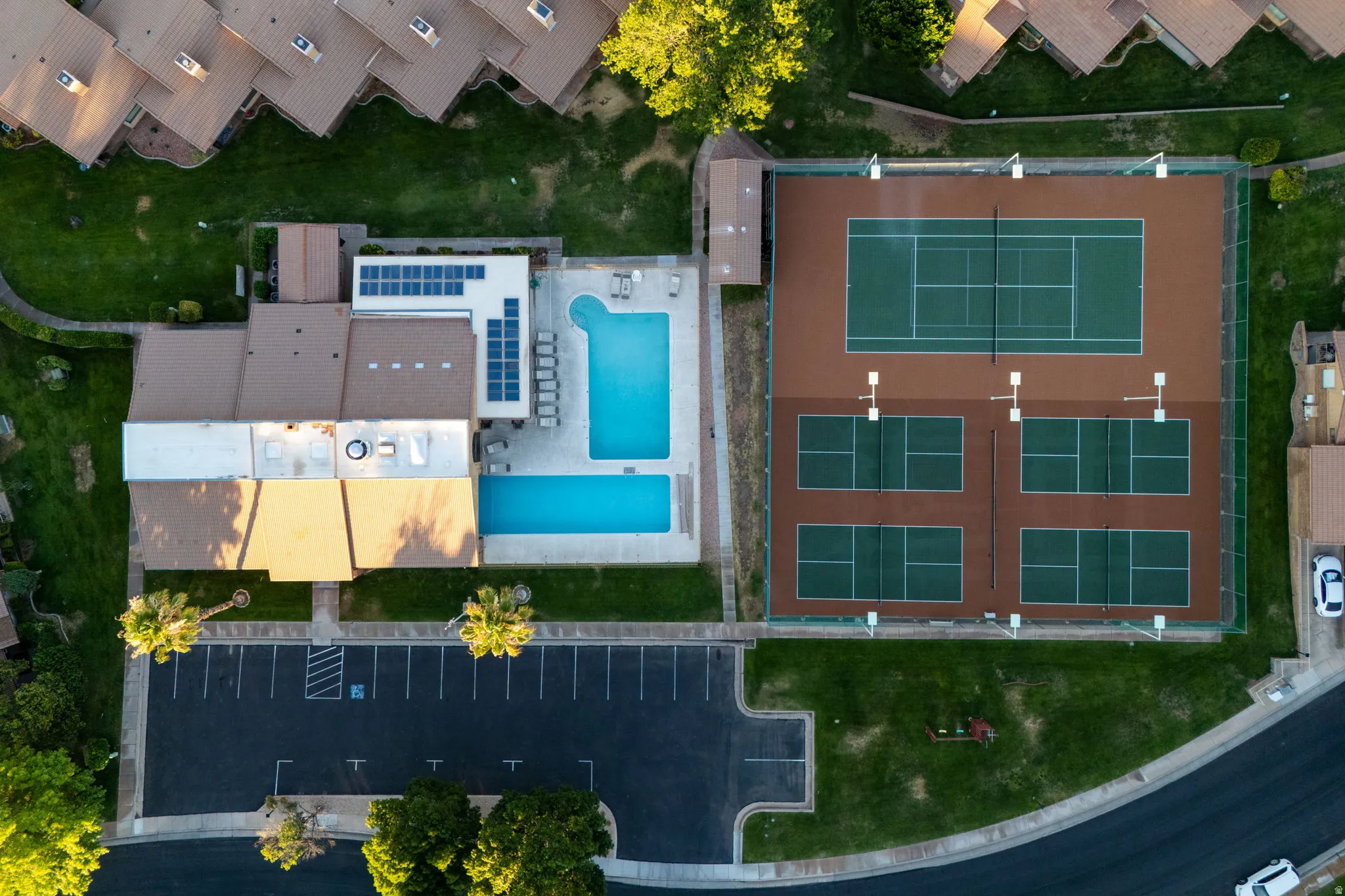Recreational complex featuring two swimming pools, solar panel arrays, a full-size tennis court, and four pickleball courts