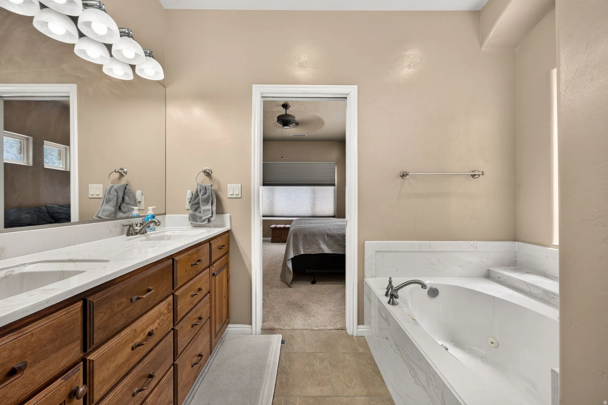 Dual vanity with white undermount sinks, wood-finish cabinetry, and a white countertop