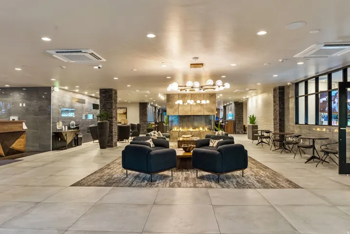 Spacious common area featuring large format tile flooring, a central linear fireplace, and integrated recessed lighting