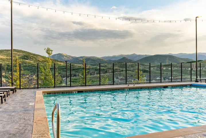 Outdoor swimming pool with a stainless steel handrail, stone coping, and textured concrete decking