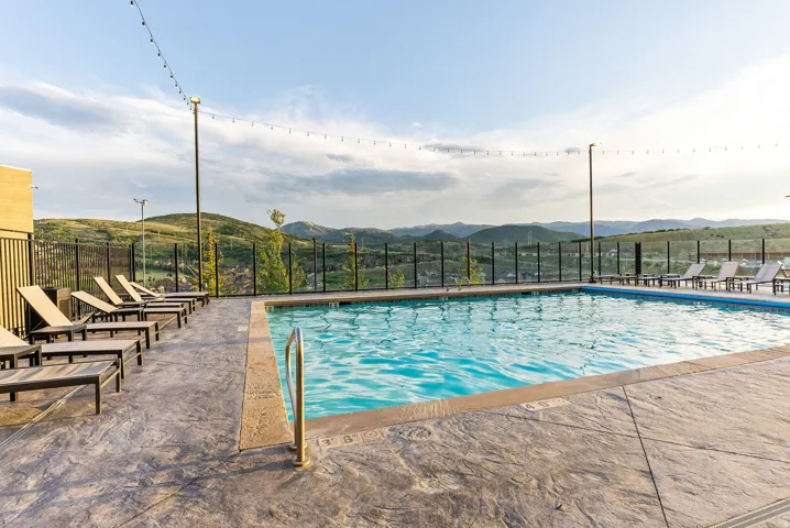 Outdoor swimming pool with stamped concrete decking and surrounding black metal fencing
