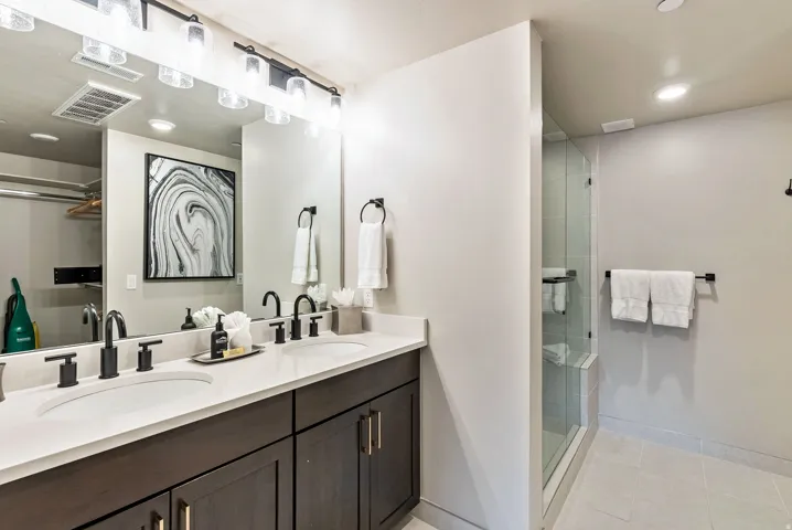 Dual vanity with dark wood-finish cabinetry, white countertop, and matte black fixtures