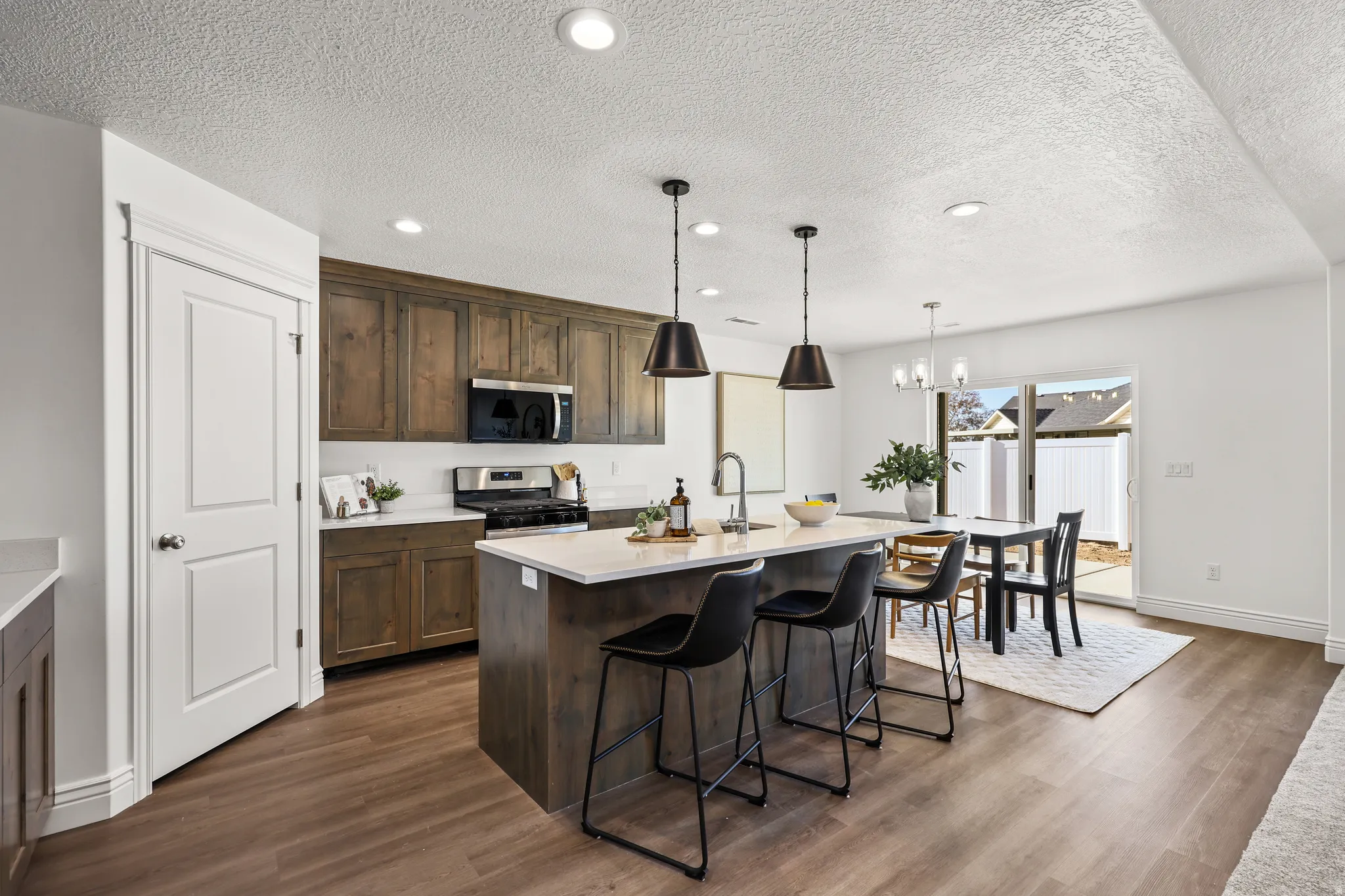 Open-concept kitchen featuring wood-finish flooring, a central island with countertop seating, stainless steel appliances, and wood cabinetry