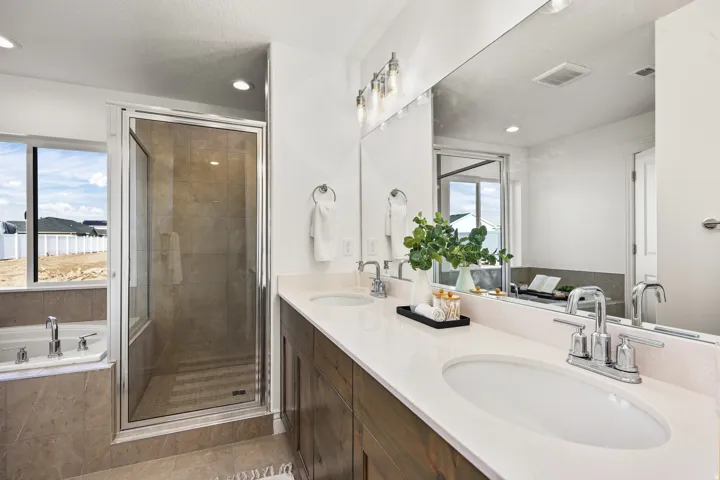 Bathroom featuring a dual vanity with undermount sinks, a walk-in shower with a glass enclosure, a built-in soaking tub, and recessed lighting