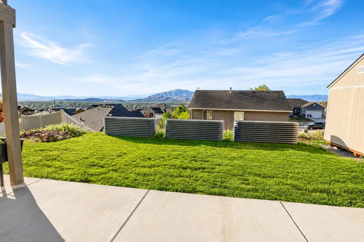 Expansive backyard featuring a green lawn, concrete patio, and three corrugated metal raised garden beds