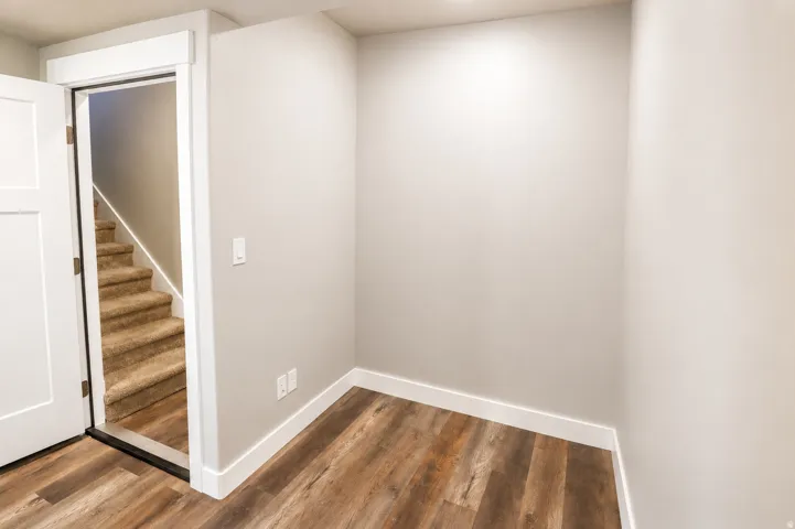 Versatile interior space featuring wood-finish flooring, light neutral wall tones, and crisp white baseboards