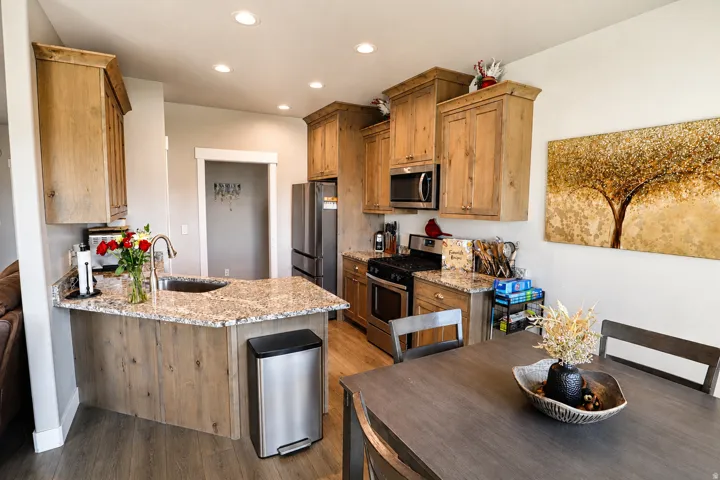 Open-concept kitchen featuring wood-finish cabinetry, granite countertops, and stainless steel appliances