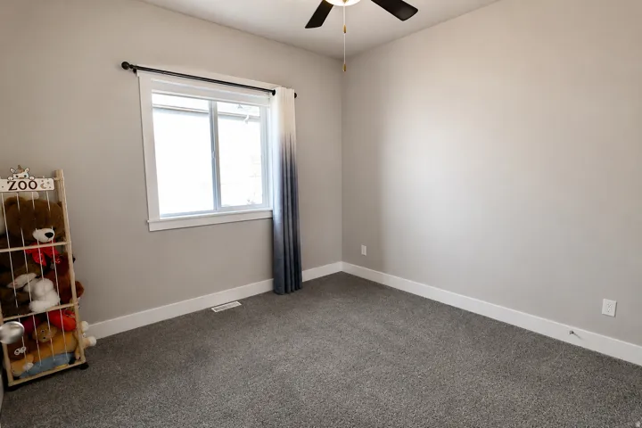 Room featuring neutral-toned walls, a large window with white trim, and dark gray carpet flooring