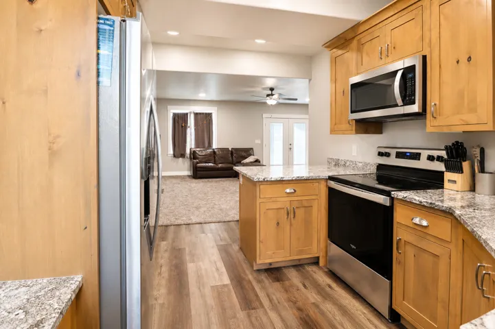 Well-appointed kitchen featuring wood cabinetry, granite countertops, stainless steel appliances, wood-finish flooring, and recessed lighting