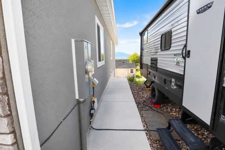 Exterior stucco siding with a concrete walkway and electrical service panel