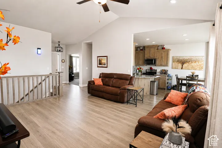 Spacious living area featuring vaulted ceilings, light wood-finish flooring, and recessed lighting