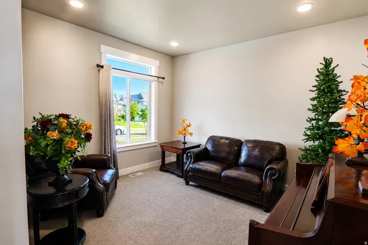 Room featuring a large window with white trim, light gray walls, recessed lighting, and light-colored carpet flooring