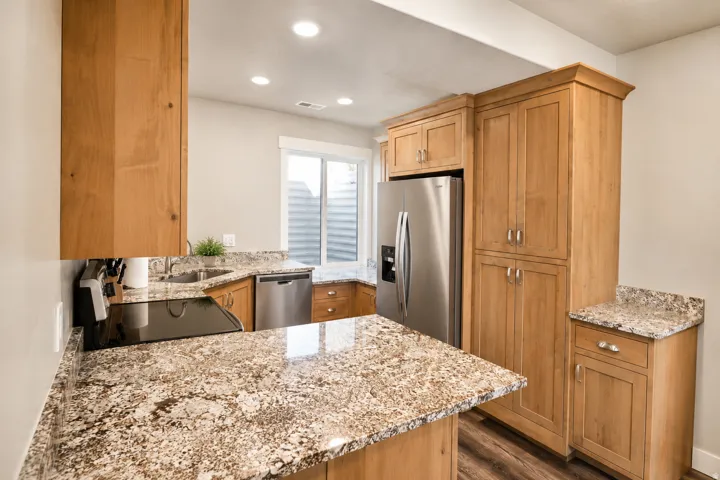 Kitchen featuring light wood cabinetry, granite countertops, stainless steel appliances, recessed lighting, and wood-finish flooring
