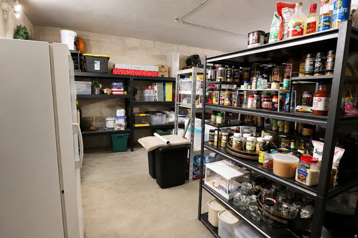 Utility room featuring a built-in shelving system, recessed lighting, concrete flooring, and an additional refrigeration unit