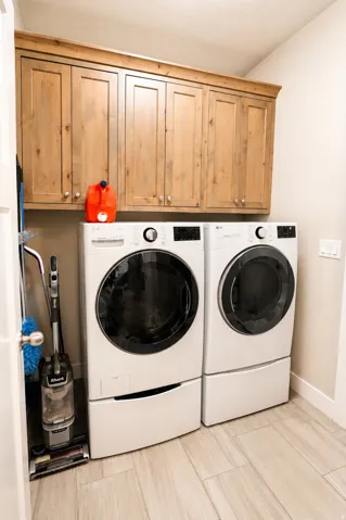 Laundry room featuring wood-finish cabinetry, light-toned wall paint, and horizontal plank tile flooring