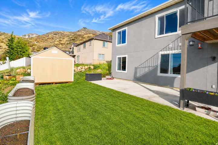 Expansive backyard featuring a manicured lawn, concrete patio, and a dedicated storage shed