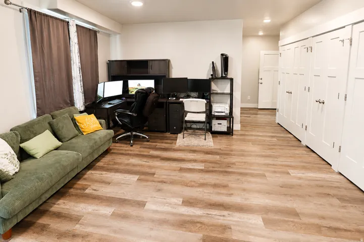 Spacious room featuring wood-finish flooring, recessed lighting, and multiple white paneled doors