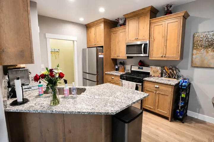 Kitchen featuring wood-finish cabinetry, stainless steel appliances, granite countertops, and recessed lighting