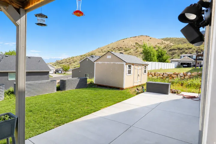 Expansive backyard featuring a concrete patio, a detached storage shed, and a grassy lawn area