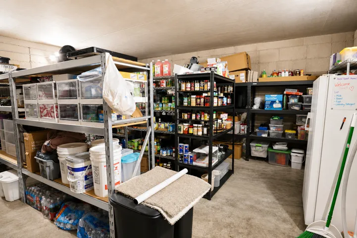 Spacious utility area featuring multiple metal shelving units, concrete block walls, and a finished concrete floor