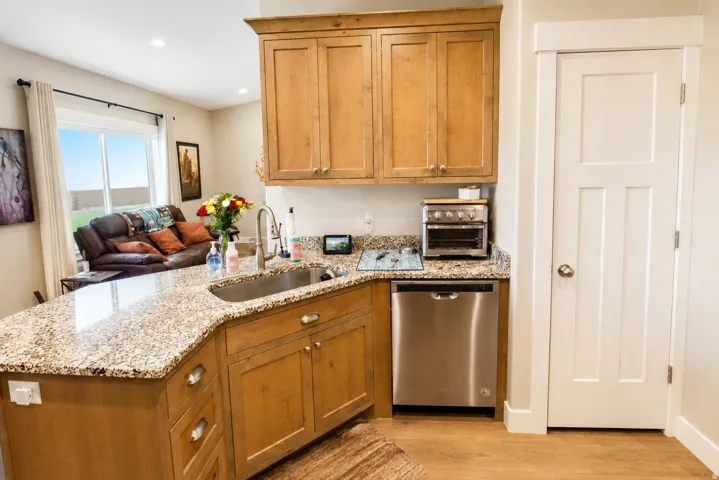 Kitchen island with a stainless steel sink, light-toned stone-finish countertop, and natural wood cabinetry