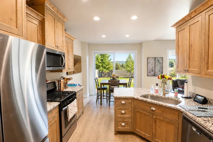 Kitchen featuring wood-finish cabinetry, granite countertops, stainless steel appliances, and recessed lighting