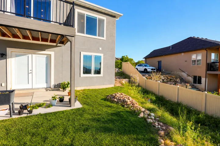 Lower level patio with double doors opening to a lush green lawn