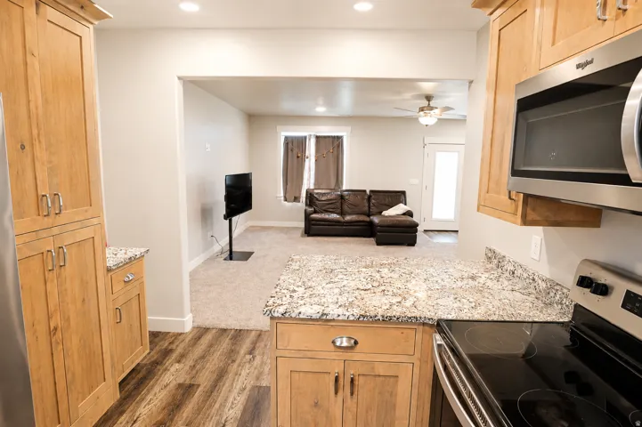 Kitchen featuring wood cabinetry, granite countertops, stainless steel microwave, and an electric cooktop