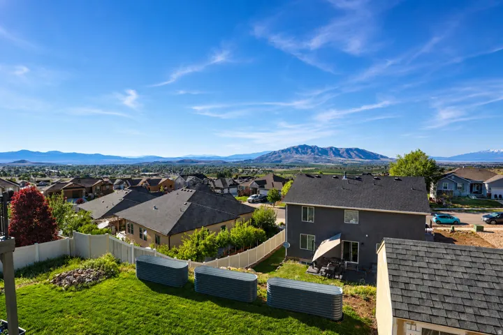 Expansive backyard featuring a green lawn, three raised garden beds, and a white privacy fence