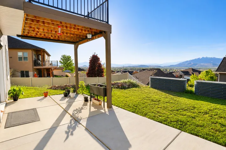 Concrete patio with an overhead deck featuring a black metal railing