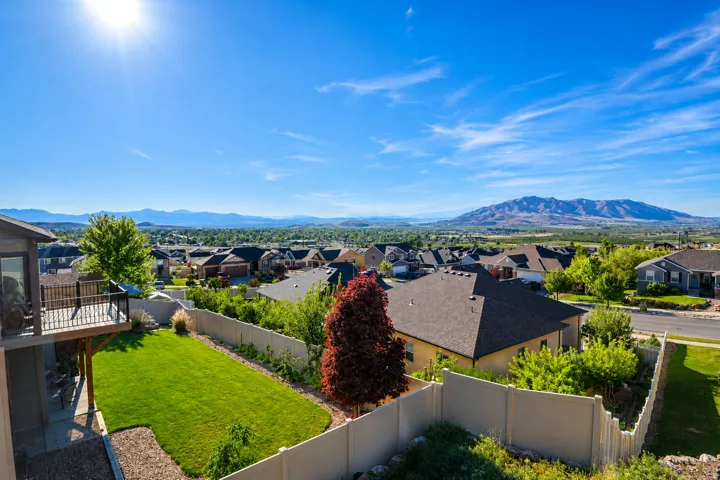 Expansive backyard featuring a green lawn, established landscaping, and a multi-level deck with black railings