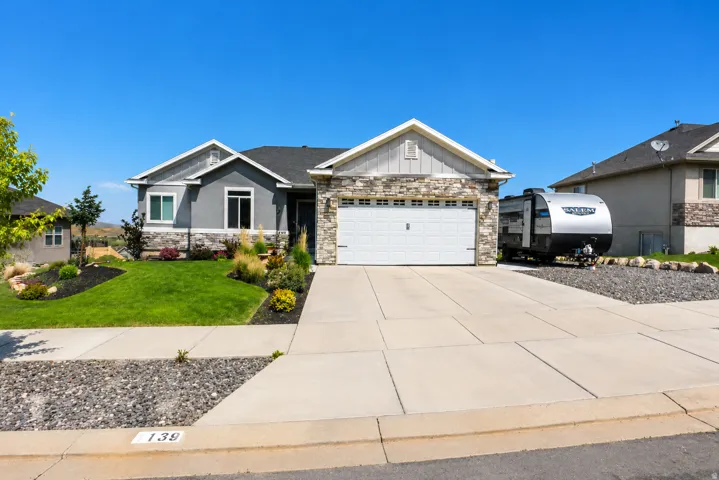 Ranch-style residence featuring a prominent two-car garage with a white panel door
