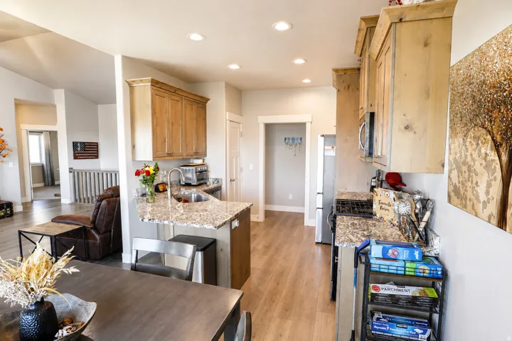Open-concept kitchen featuring wood-finish cabinetry, light-toned countertops, and stainless steel appliances
