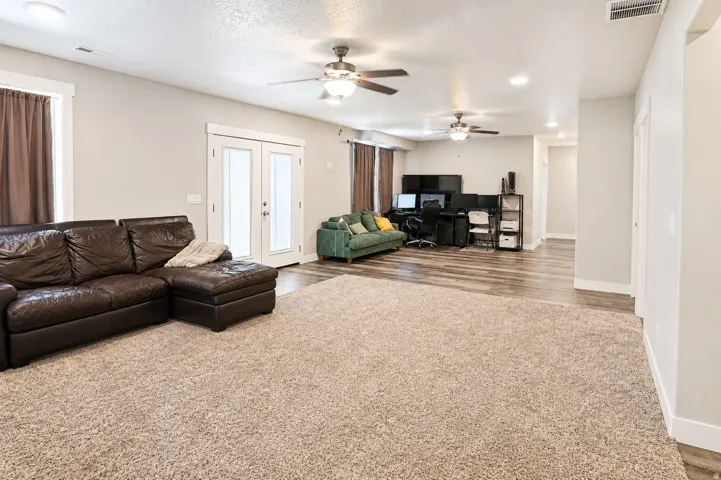 Spacious interior featuring a large carpeted area, wood-finish flooring, recessed lighting, and multiple ceiling fans